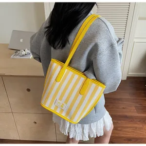 Vue détaillée du sac cabas à rayures jaunes avec poignée en cuir et étiquette tissée