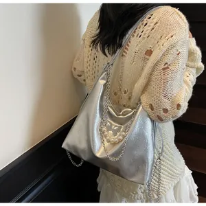 Detailed texture of silver crinkled hobo bag with butterfly and pearl chain details