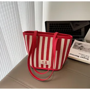 Détail d'un sac cabas à rayures rouges et blanches avec logo DAXI et anses en cuir