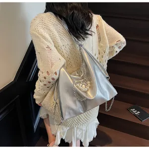 Silver metallic tote bag with chain strap and pearl heart pendant on a shoulder bag
