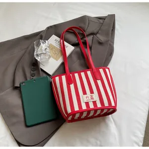 Détail du cabas en toile à rayures rouges et blanches avec étiquette DAXI et bandoulières