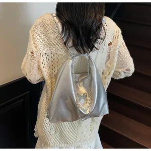 Macro view of silver metallic pleated tote bag with pearl and butterfly charms on shoulder