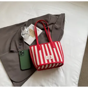 Vue détaillée du sac cabas en toile à rayures rouges avec logo et accessoires de mode