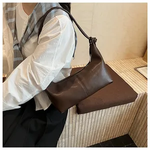 Detail of dark brown leather hobo bag featuring a decorative knot on the shoulder strap