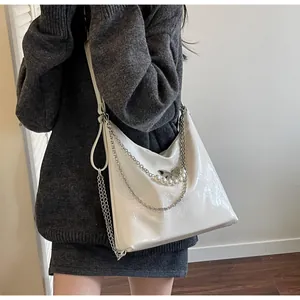 Close-up of white glossy tote bag with silver butterfly, chain and pearl charms