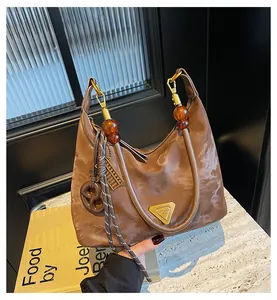 Dettaglio borsa tote marrone con perle d'ambra, placca dorata e ciondolo a abaco