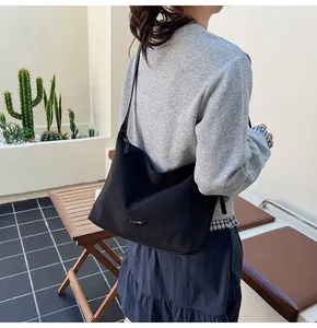 Lifestyle view of the black hobo bucket bag styled with a grey sweatshirt for a casual look