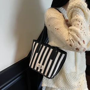 Grand sac cabas à rayures avec étiquette DAXI porté par un mannequin pour l'été