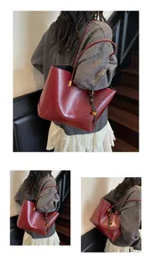 Detailansicht einer burgunderroten Leder-Tote-Bag mit goldenen Beschlägen und Knotendetail