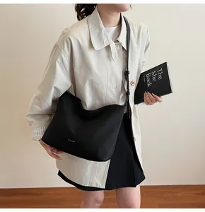 Street style view of a large black casual crossbody bag with a minimal CLEAR K brand label