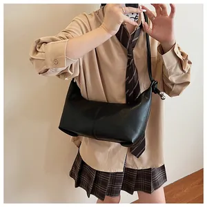 Detail of black leather dumpling bag with knotted strap worn with preppy style outfit
