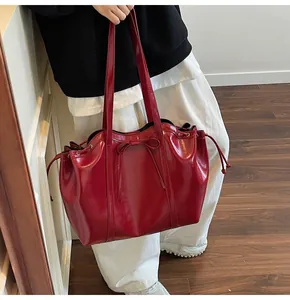 Rote glänzende Totebag mit Schleife an der Schulter in minimalistischem Innenraum