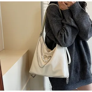 Detailed shot of glossy cream white hobo bag with silver chains and butterfly pearl charm