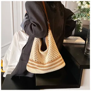 Dettaglio borsa da spiaggia intrecciata con trama a maglia e manici in pelle marrone
