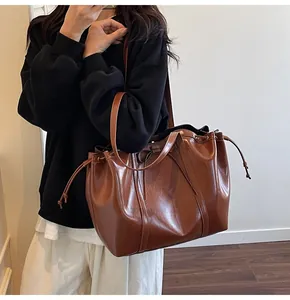 Detail der tiefbraunen glänzenden Ledertasche mit Kordelzug und Schleifen-Applikation