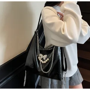 Detail of black glossy tote bag with silver butterfly charm and pearl chain decoration
