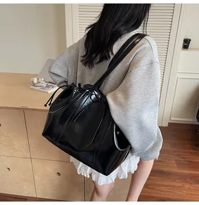 Detailed view of large black glossy tote bag with drawstring on a female model