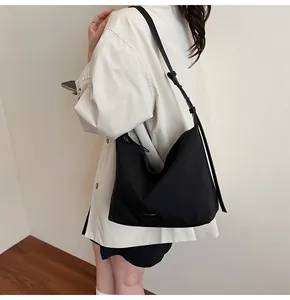 Close-up of black nylon hobo bag showing adjustable strap and minimalist brand label