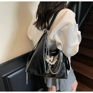 Detail of black glossy tote bag with silver chain and white pearl butterfly charms