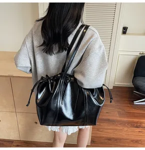 Detailed back view of a black glossy leather tote bag with elegant drawstring design