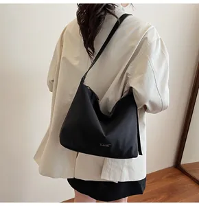 Close-up of black minimalist hobo bag with nylon texture and metal logo tag details