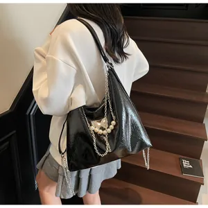 Close-up of black glossy tote bag with silver chain, pearl charms and butterfly pendant