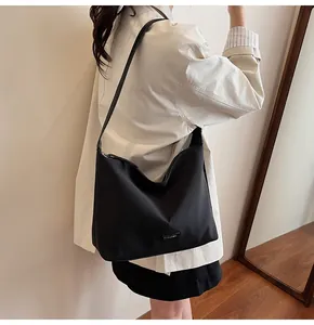 Minimalist black bucket bag with CLEARVK metal logo worn by model in a cozy interior