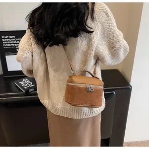 Detailed view of brown matte leather handbag with dual silver zippers and top handle