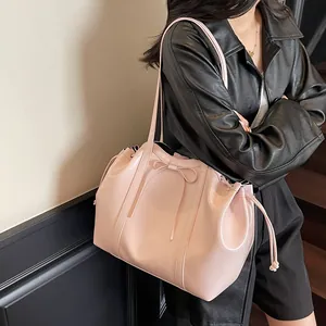 Rosa glänzende Tote-Schultertasche mit Schleife, präsentiert von einem Model vor einer Wand