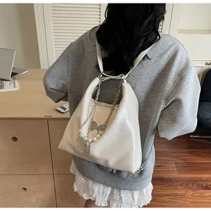 Detailed view of the off-white glossy backpack with pearl and silver chain decorations