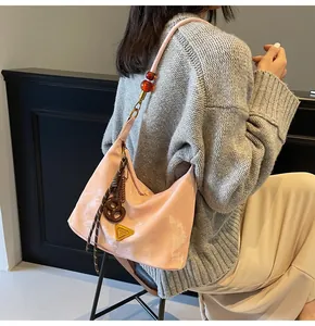 Dettaglio borsa hobo rosa con motivo a nuvole, perle ambrate e ciondolo a forma di pretzel