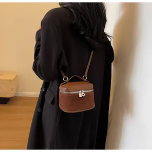 Detail of a brown leather crossbody box bag shown on a model in a minimalist setting