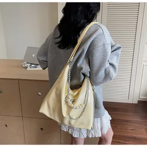 Detail of light yellow PU leather tote bag with metal butterfly and pearl chain strap
