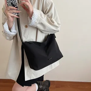 Minimalist black nylon bucket bag with adjustable strap worn as a crossbody shoulder bag