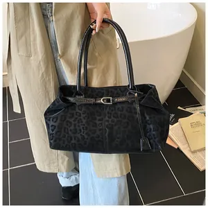 Dettaglio della borsa tote leopardata nera con manici in pelle e fibbia decorativa