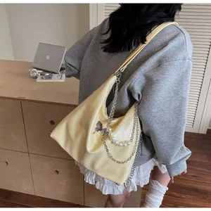Detail of yellow glossy hobo bag with silver butterfly charm and pearl chain strap