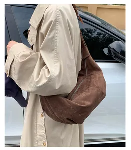 Sac bandoulière en suédine marron porté par un mannequin en trench beige élégant et décontracté