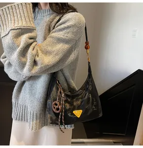 Dettaglio della borsa hobo nera marmorizzata con logo in metallo e ciondolo a brezel