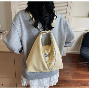 Pale yellow tote backpack showing butterfly buckle and pearl chain details on back