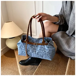 Dettaglio della borsa tote blu con stampa leopardata, manici in pelle e fibbia dorata