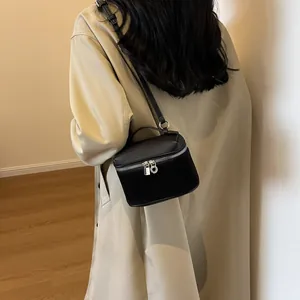 Chic black textured leather crossbody box bag with top handle shown on a model