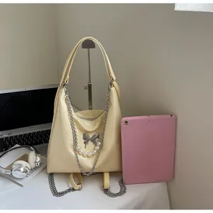 Detail of cream leather tote bag with silver butterfly charm and decorative pearl chain