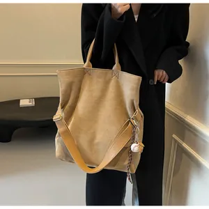 Sac fourre-tout en daim marron avec bandoulière et breloque baseball, style minimaliste