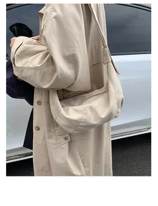 Détail d'un grand sac cabas beige mat avec bandoulière large et texture douce en plein air