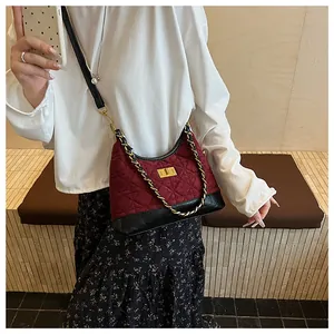 Dettaglio borsa trapuntata bordeaux con chiusura girevole oro e finiture in pelle
