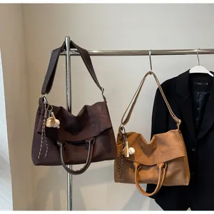 Détail de grands sacs cabas en daim marron et beige avec bandoulières et accessoires