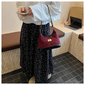 Dettaglio borsa trapuntata bordeaux con catena dorata e elegante chiusura girevole retrò