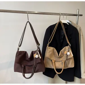 Détail de sacs à bandoulière en daim marron avec pendentifs de baseball et sangles en cuir