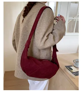 Détail du sac demi-lune en daim bordeaux avec large bandoulière et fermeture éclair