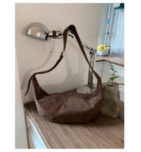 Détails du sac bandoulière en daim marron foncé avec patchwork sur une table en bois rétro